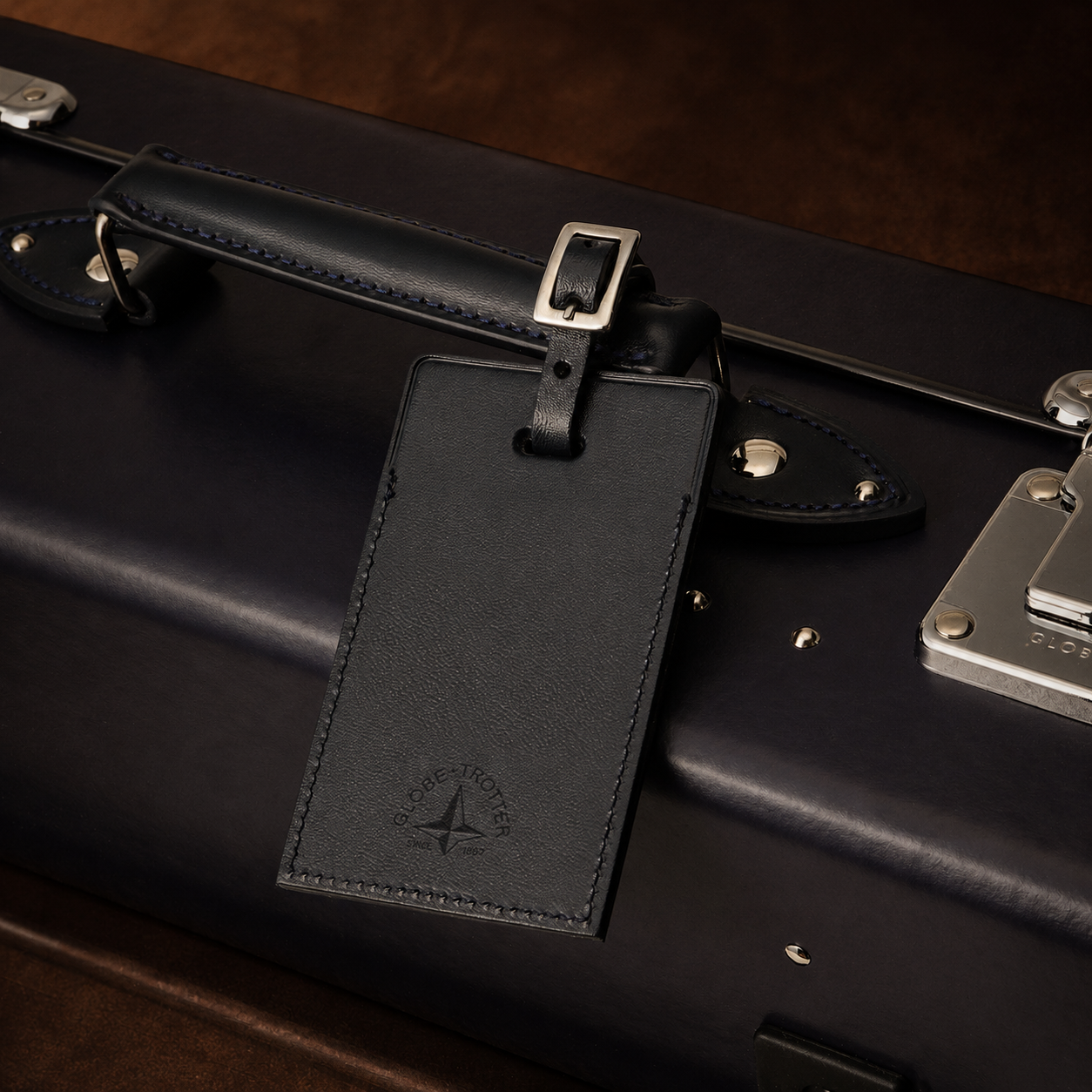 Black leather suitcase with a matching luggage tag on a dark surface